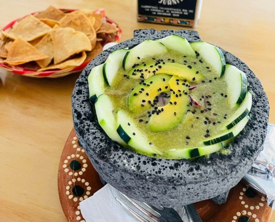 Aguachile con pepino servido en un molcajete, acompañado de totopos.