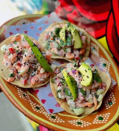 Tostadas de camarón con rodajas de aguacate y salsa.